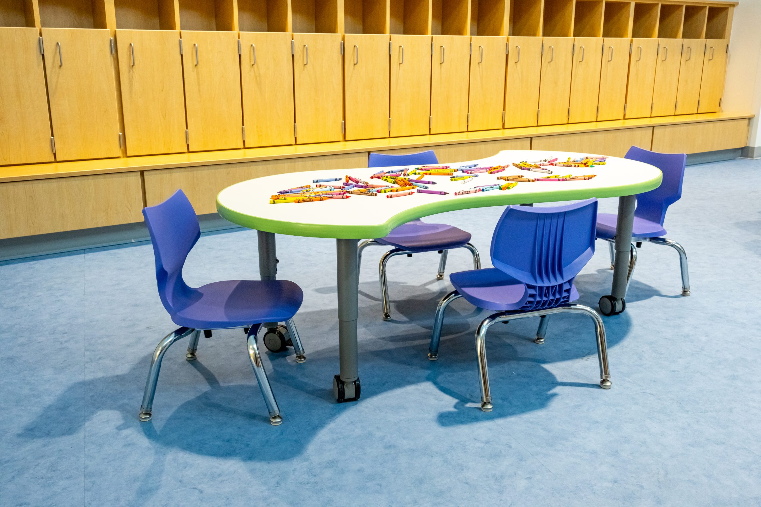 a child sized wave shaped table with four blue chairs