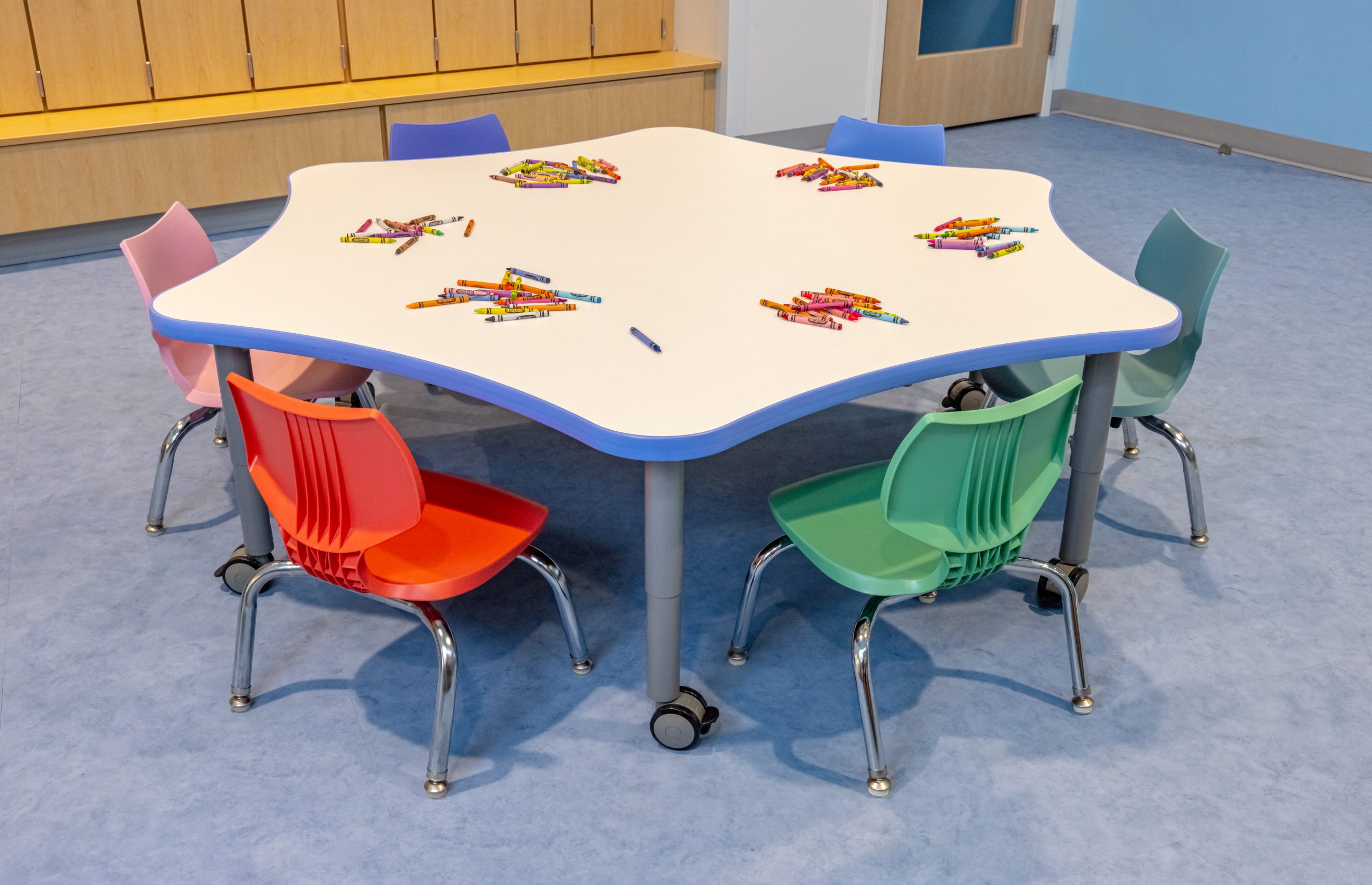 a child sized star-shaped table with 5 multicolored chairs