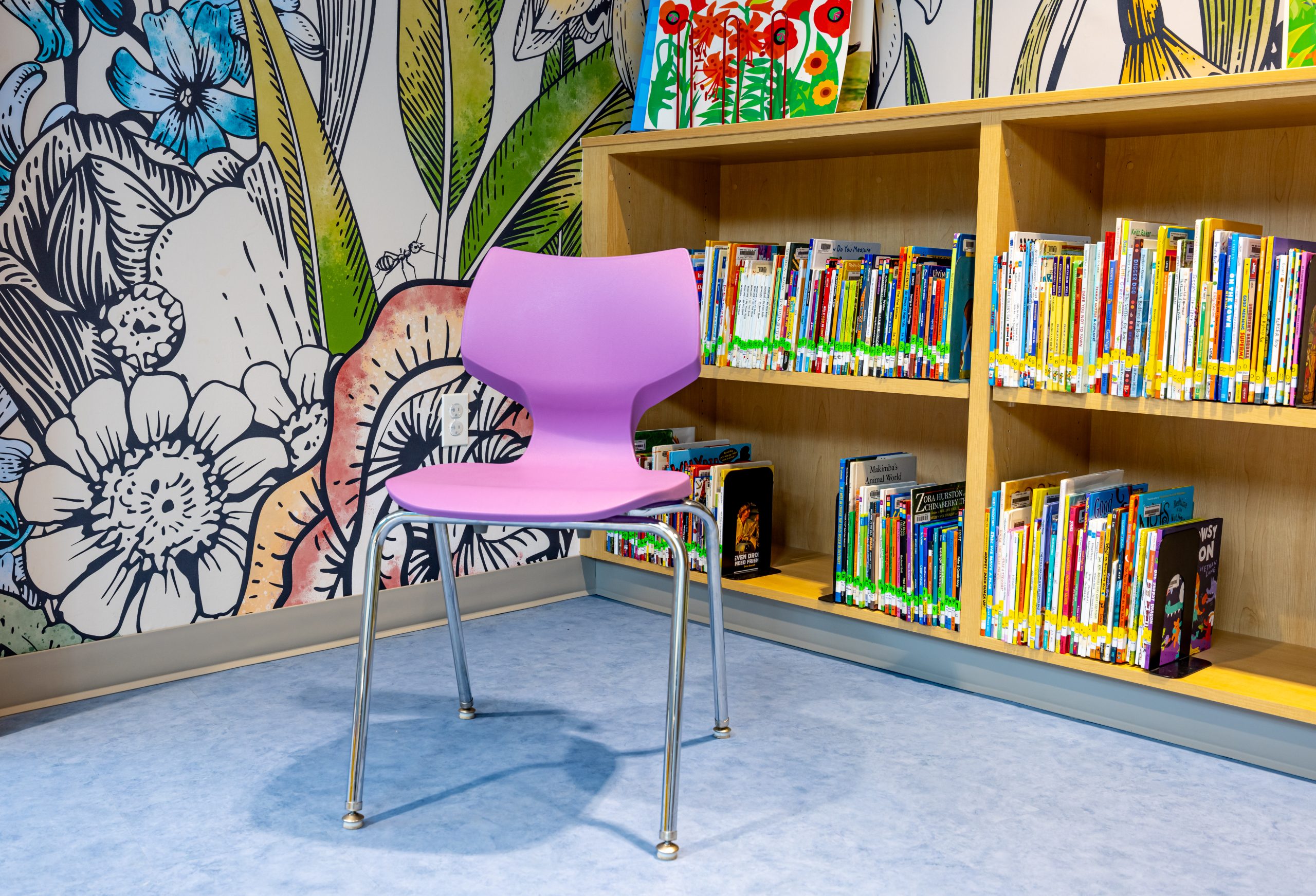 a bright purple chair against a backdrop of library books on shelves