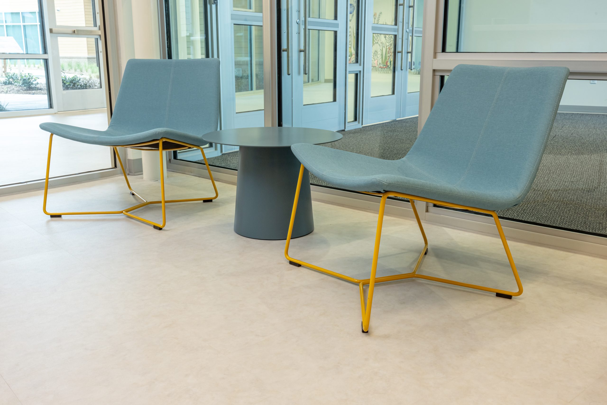light blue lounge chairs with yellow legs and a small circular side table