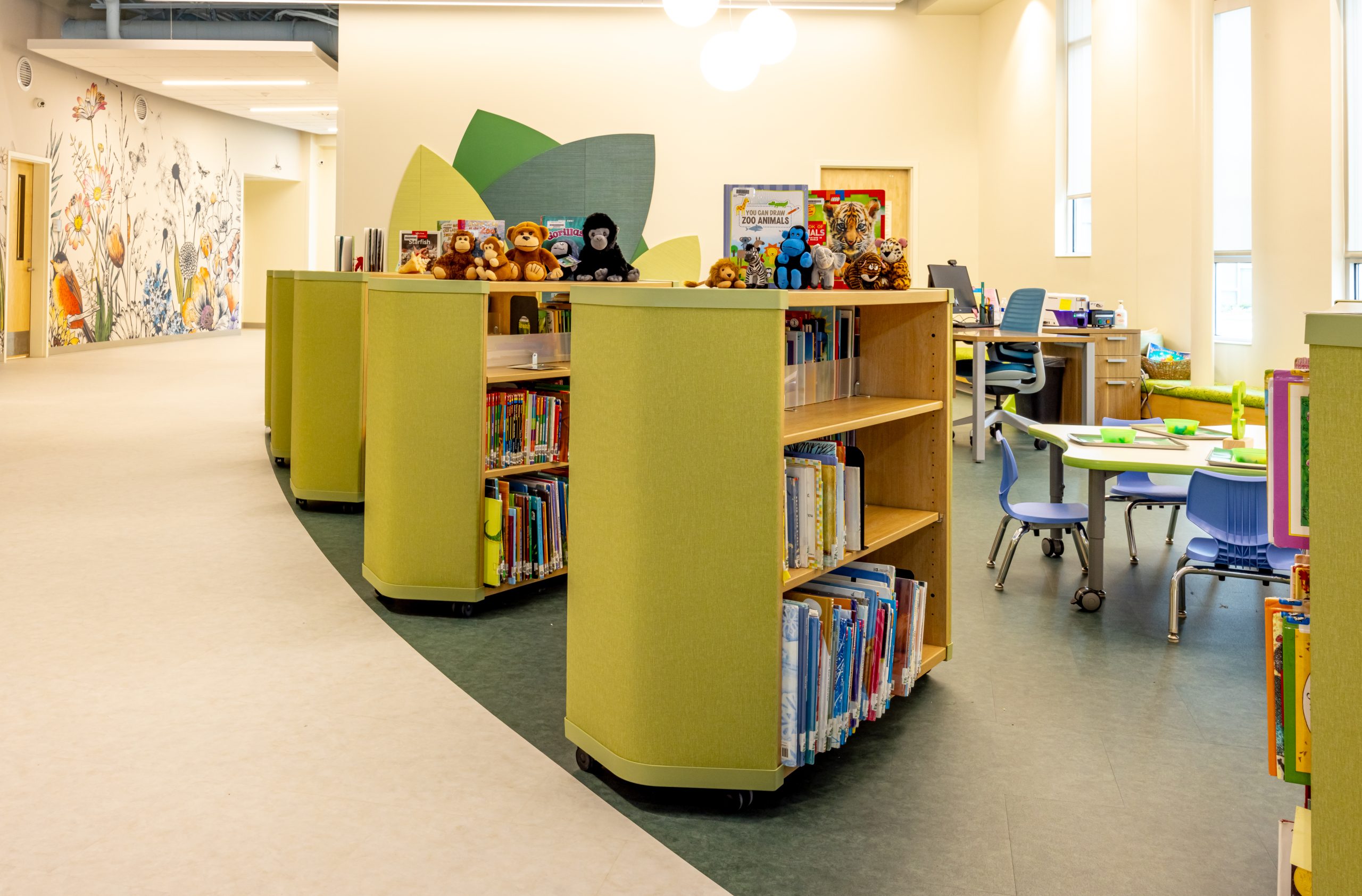 interior of a preschool library with mobile bookcarts, bookshelves, tables and chairs