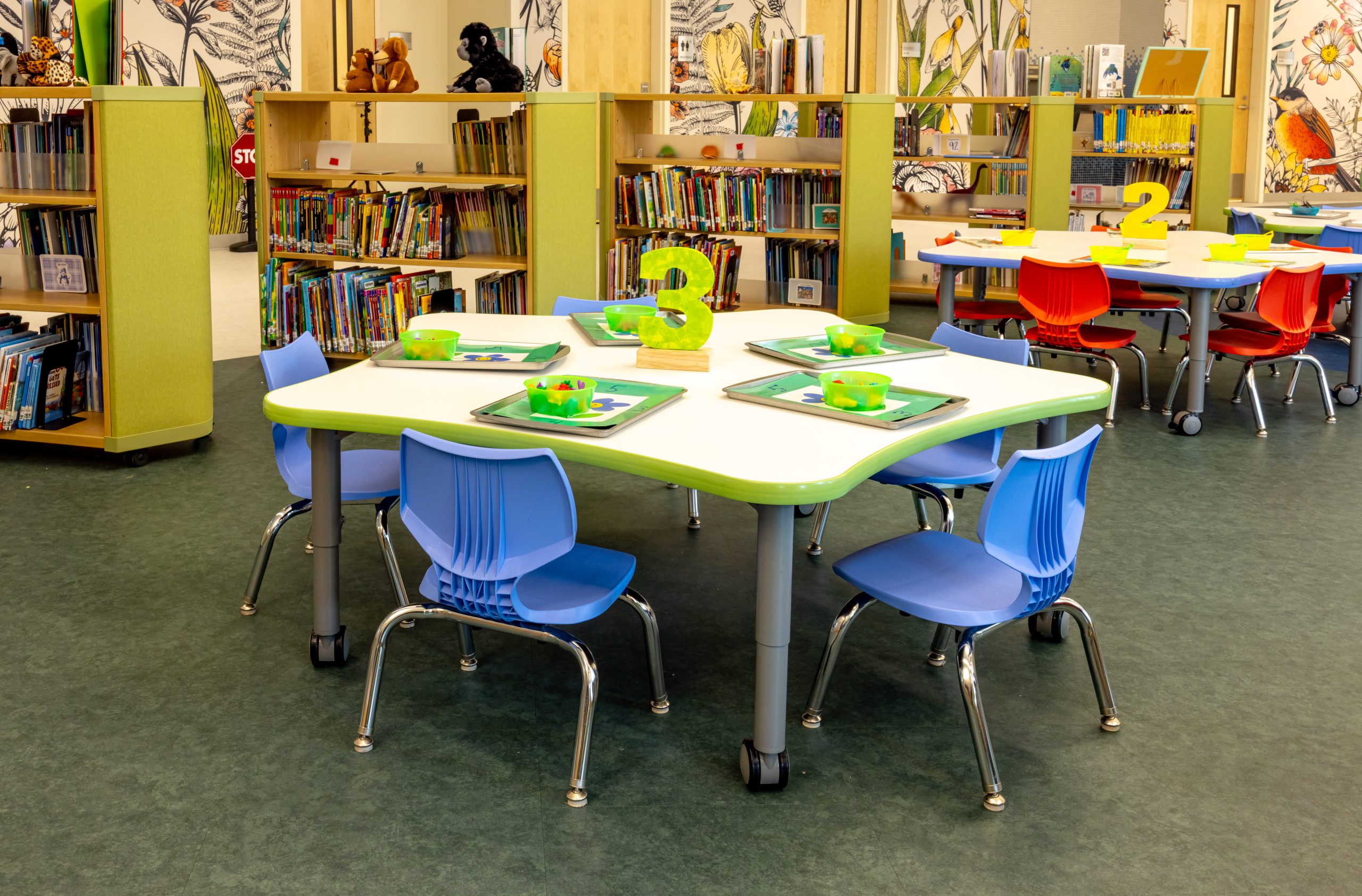 interior of a preschool library with mobile bookcarts, bookshelves, tables and chairs