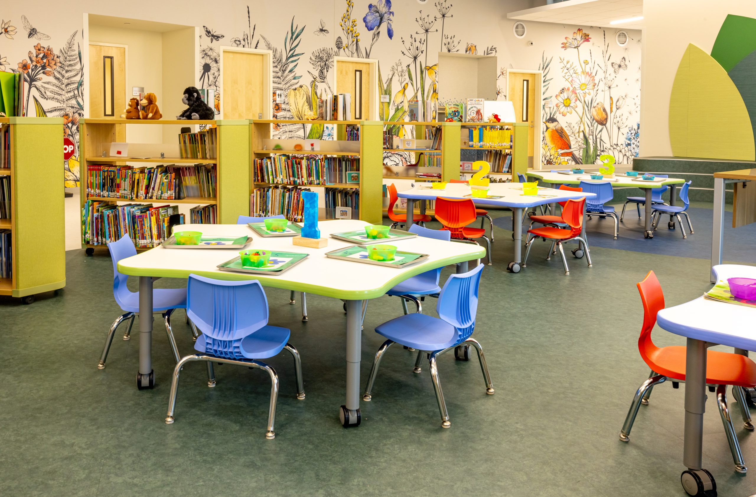 interior of a preschool library with mobile bookcarts, bookshelves, tables and chairs
