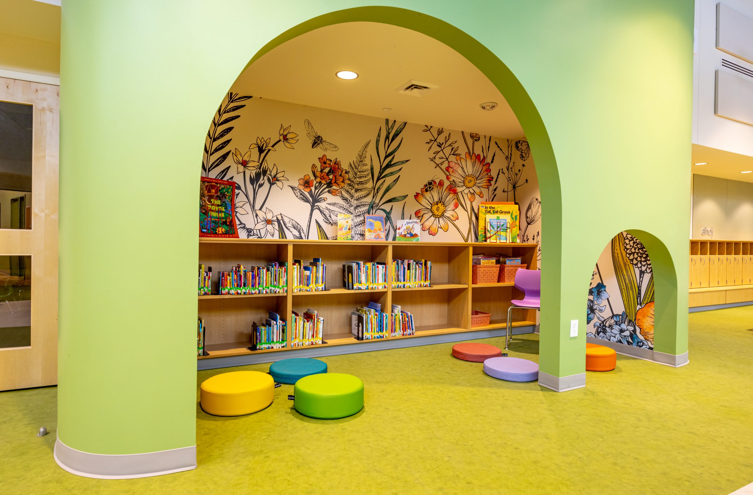 reading nook of a preschool library with books on shelves and colorful floor cushions