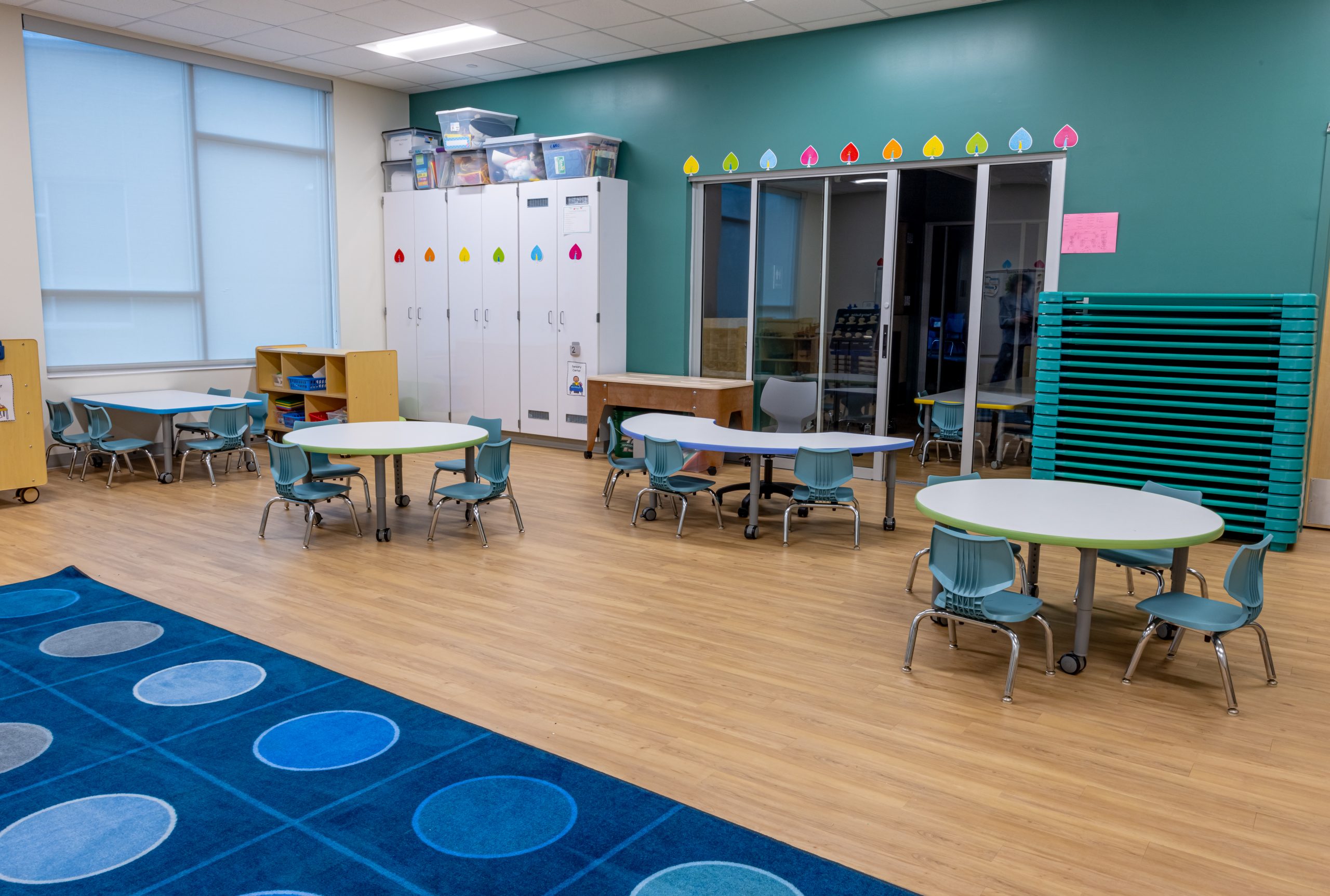 interior of a preschool classroom with colorful carper, tables and chairs