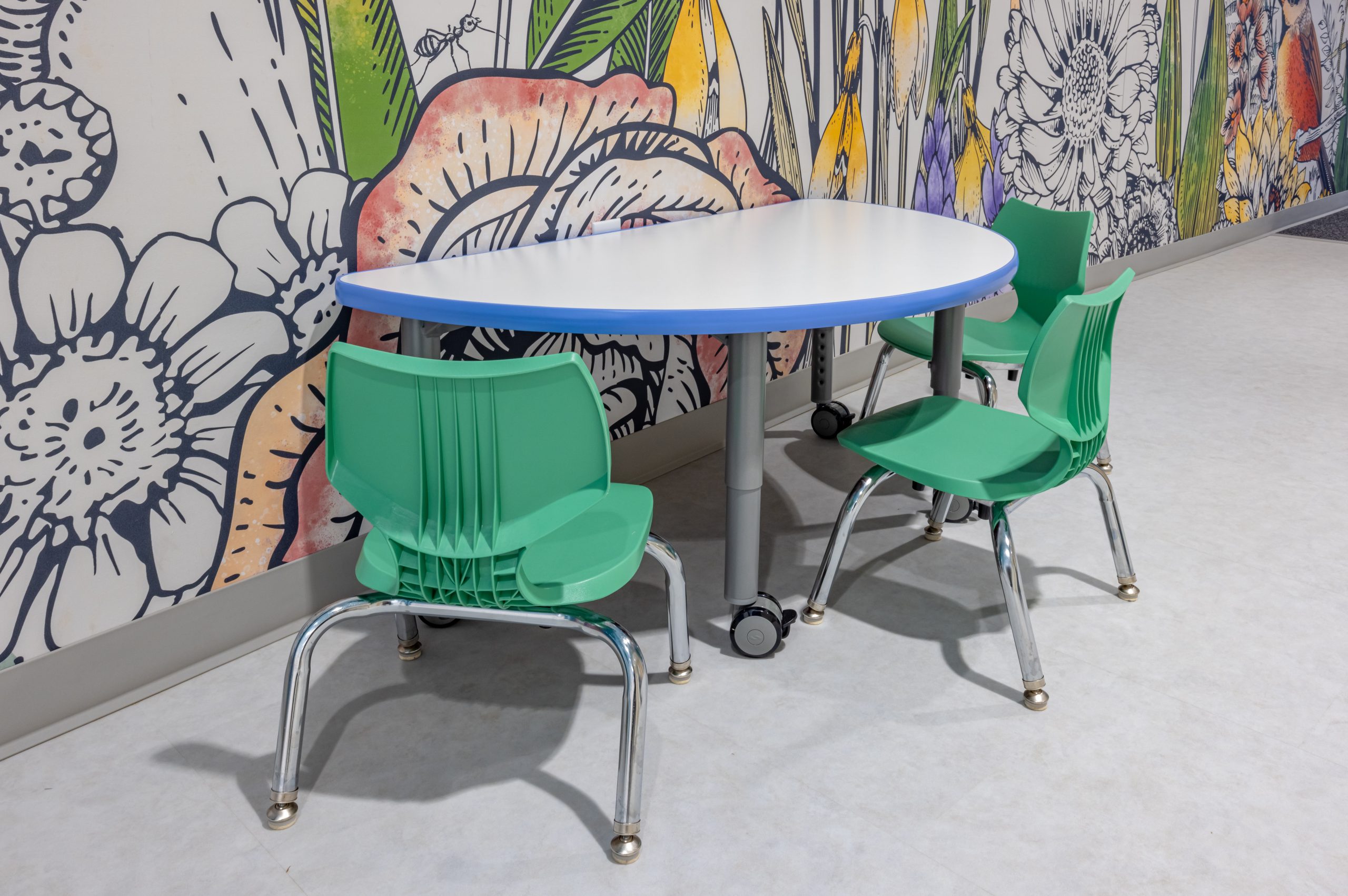 a child sized half circle table with 3 green chairs